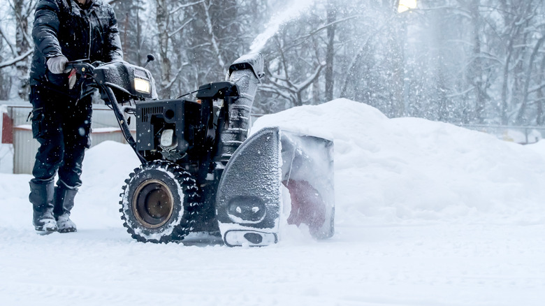 person pushing snow blower outside to remove snow