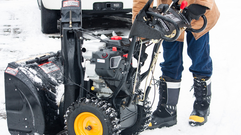 person leaning down to test snow blower