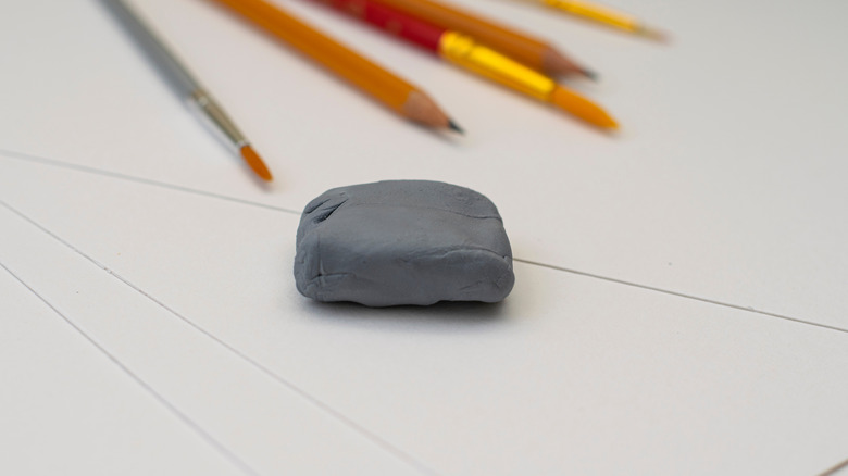 Kneaded eraser on a paper with paint brushes and pencils