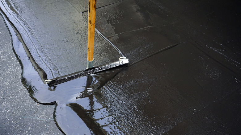 person sealing asphalt
