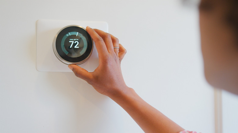 Person adjusting temperature on smart thermostat