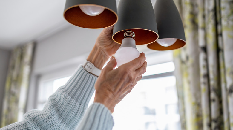 Senior woman placing LED bulbs in light fixture