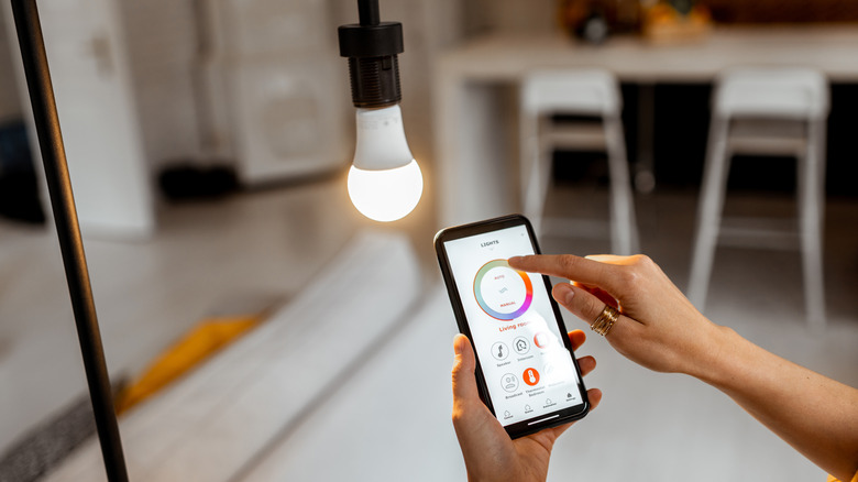 Woman adjusting smart bulb from smartphone app