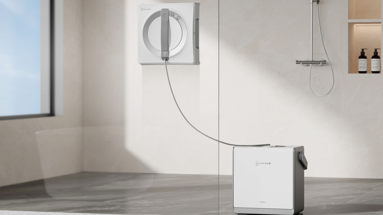 An ECOVACS window cleaner attached to a glass shower door