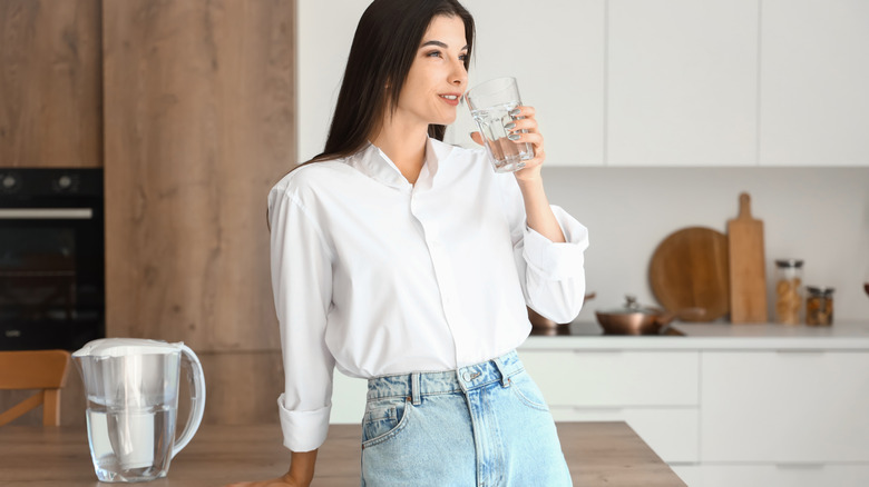 A person drinking filtered water in kitchen