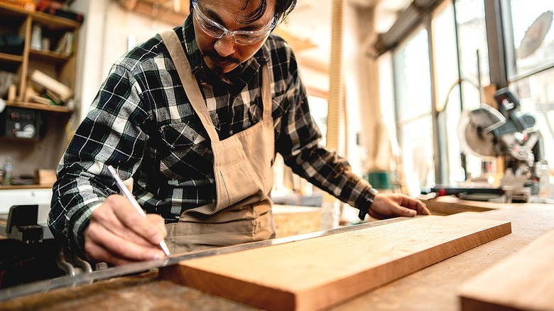 Person wearing eye protection works in their workshop on a piece of wood