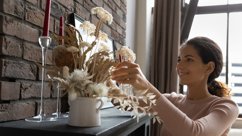 A person styles a fireplace mantel in the living room of a condo.