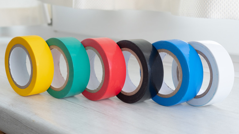Colorful rolls of electrical tape are lined up on a counter