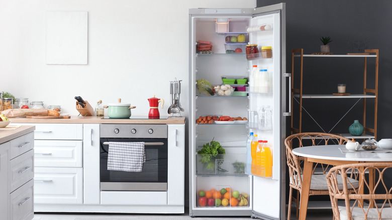 An open refrigerator on the end of cabinets in a kitchen
