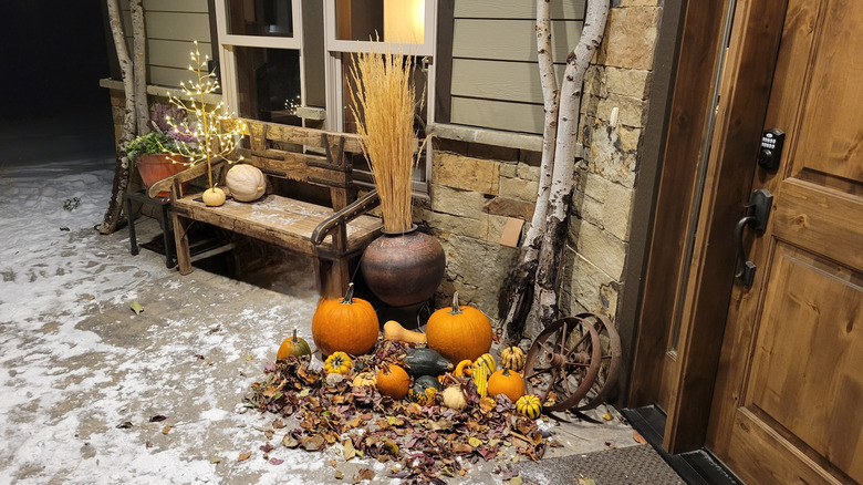 Rustic fall decor and pumpkins next to a front door