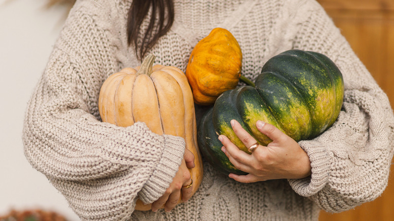 A person holding pumpkins on a porch