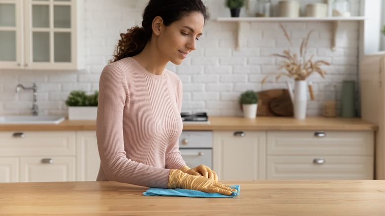 A woman cleans a kitchen countertop
