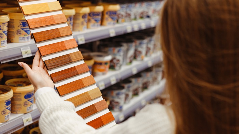 A woman examines wood stain samples in a store