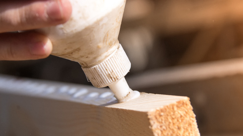 Person applying glue to a wood board