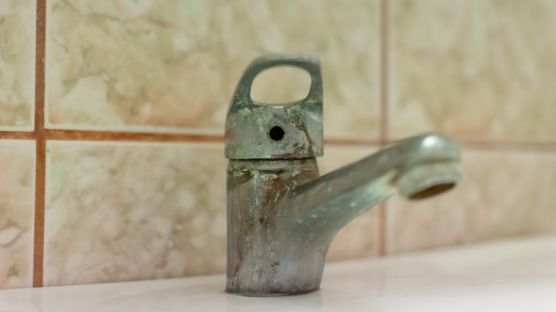 Close-up of a bathroom faucet covered with heavy limescale and mineral deposits