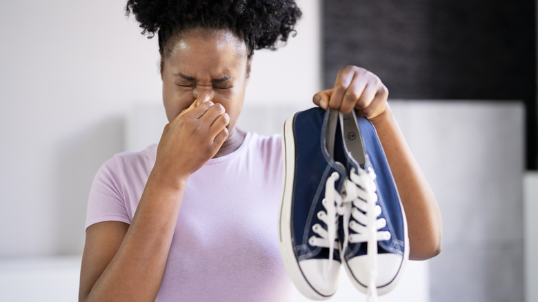 Woman plugging nose holding shoes