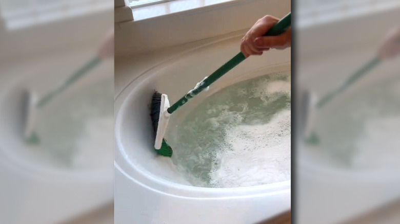 Woman scrubbing her tub with a broom