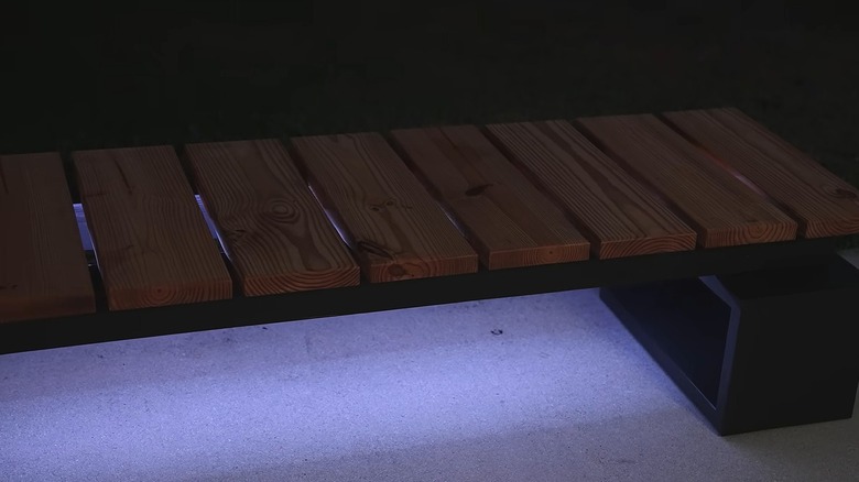Modern bench with a wooden seat and black legs with LED lights under the seat
