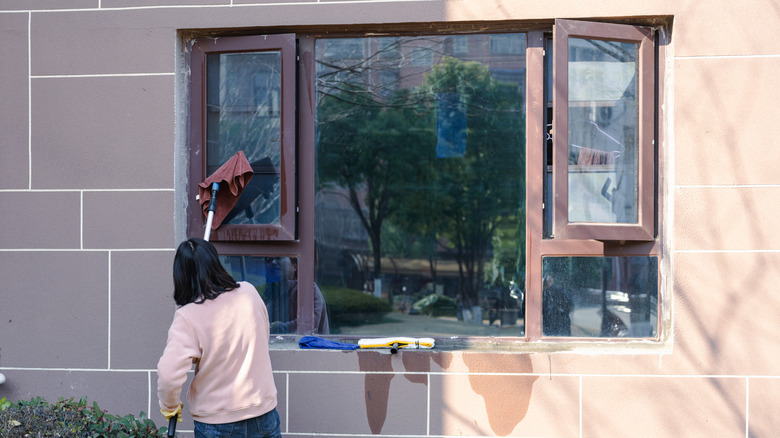 Woman washing her home's exterior windows