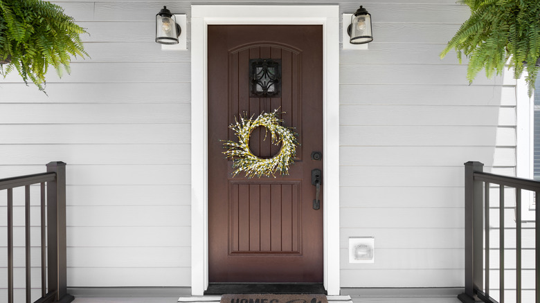 a brown front door on a gray vinyl-sided home