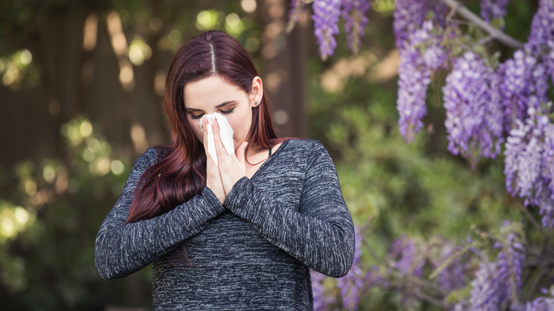 Woman sneezing in garden