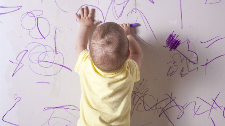 Child coloring on wall