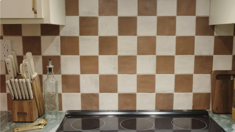 A kitchen backsplash with brown and white checkered tiles.