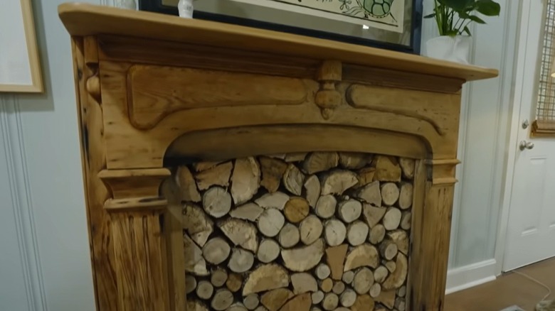 A rustic wooden fireplace mantel filled with hardwood