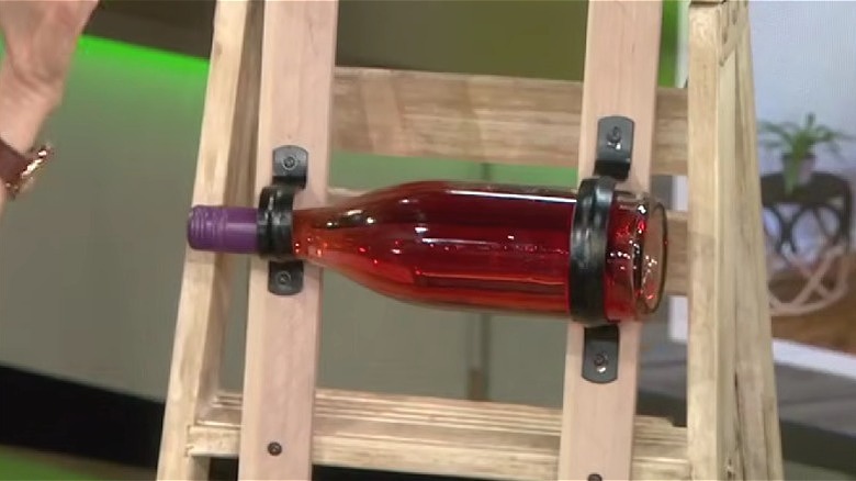 Brackets attached to the back of a wood ladder so it can store wine bottles.