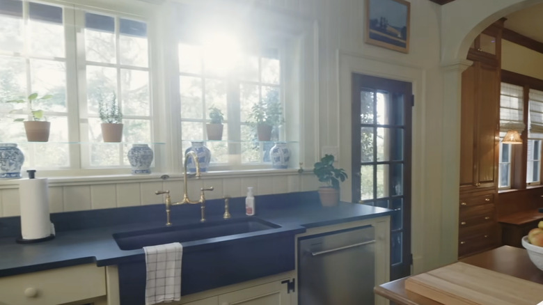 A kitchen with V-groove backsplash paneling, French windows, and black countertops.