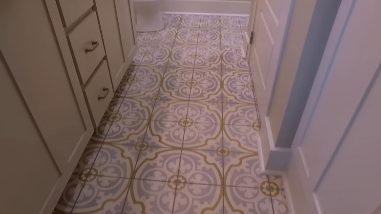 A narrow bathroom floor with patterned tiles