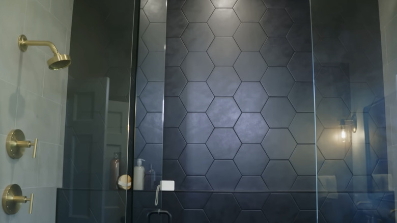 A modern shower with black hexagonal tile