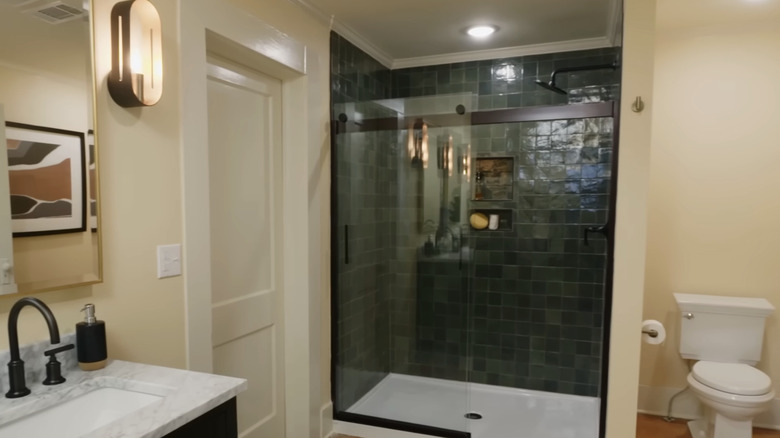 A bathroom with a dark green tiled shower