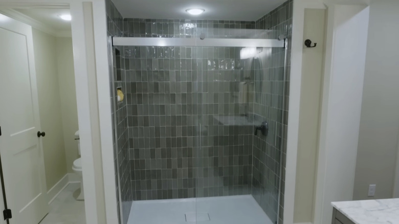 A large shower with vertical green rectangular tiles