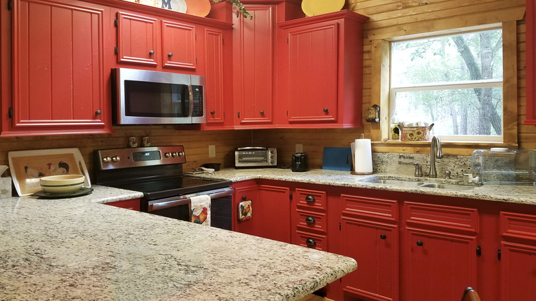 A kitchen with dark red cabinets