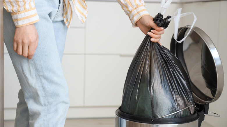 A person taking out the kitchen trash