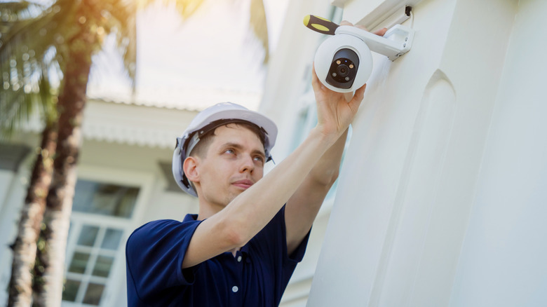 A technician installing a security camera outside a house