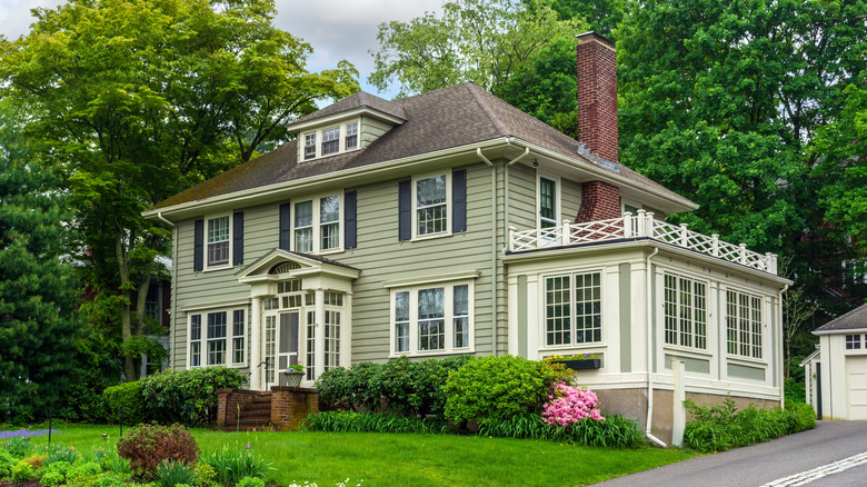 A Colonial-style pale green house with a dormer window.