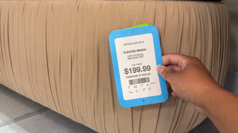 Female hands holding the price tag of a bench with storage at HomeGoods