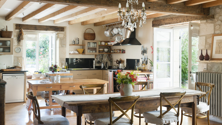 A French-style, maximalist rustic wooden kitchen with exposed wood beams