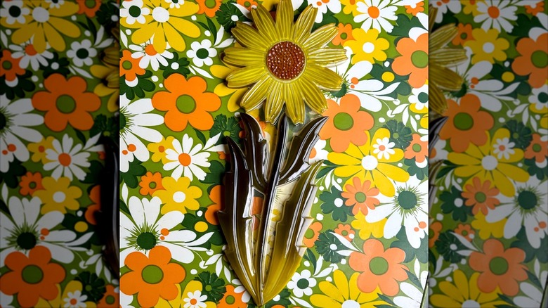 Vintage Lucite daisy wall plaque with dark green leaves.