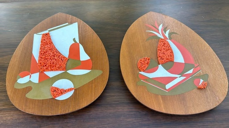 Matching set of wood popcorn art, one with a pear, one with a pineapple, on a wooden table