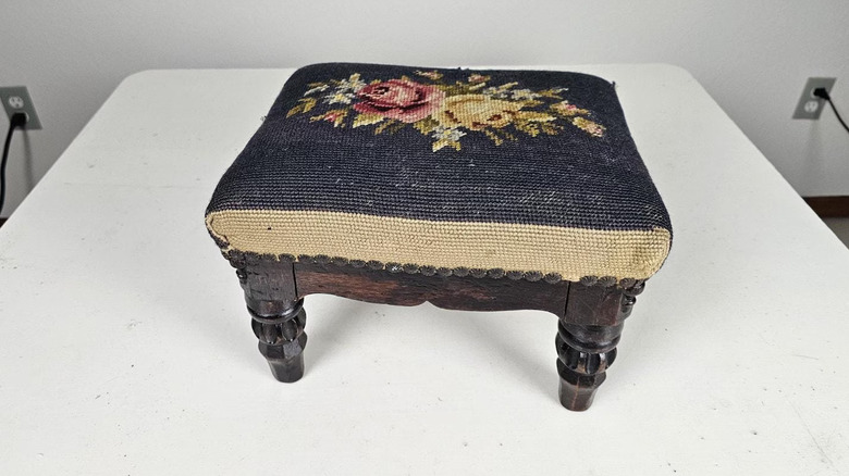 A small vintage needlepoint top footstool with floral design