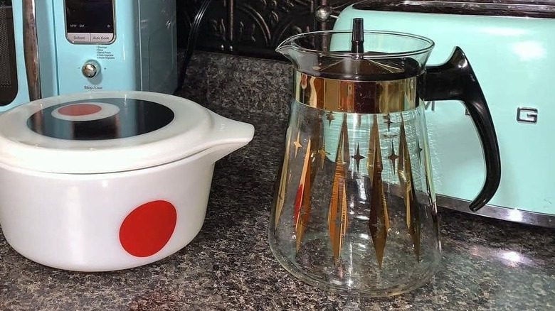 Atomic patterned Pyrex carafe on a kitchen counter next to a white and red casserole dish.