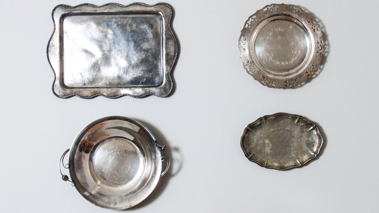 Collection of four silver trays hanging on a wall, each with a different style