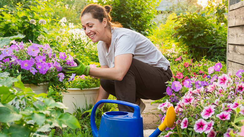 Woman squatting in garden looking at colorful flowers with a big smile on her face