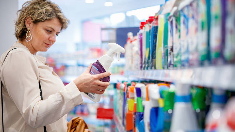 Woman in store reading bottle of cleaning solution