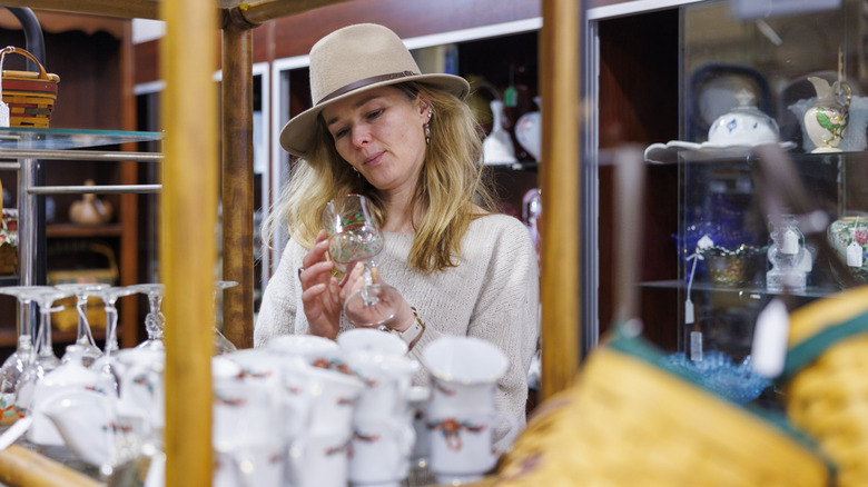A woman looking at glassware in an antique store
