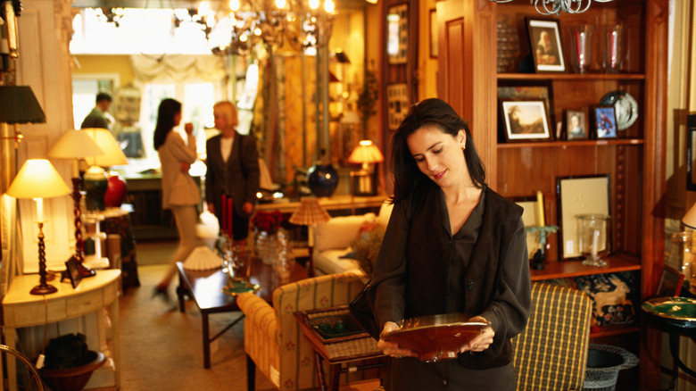 woman examining bowl in an antique shop