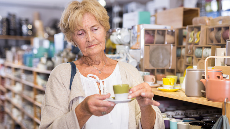 An older woman looking at vintage dishware in a thrift store